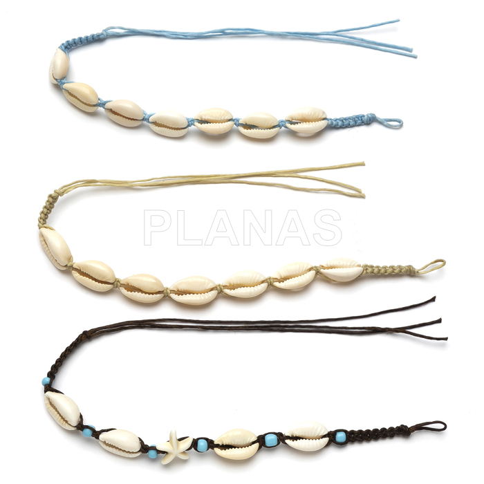 Pulseiras ou tornozeleiras trançadas com conchas.