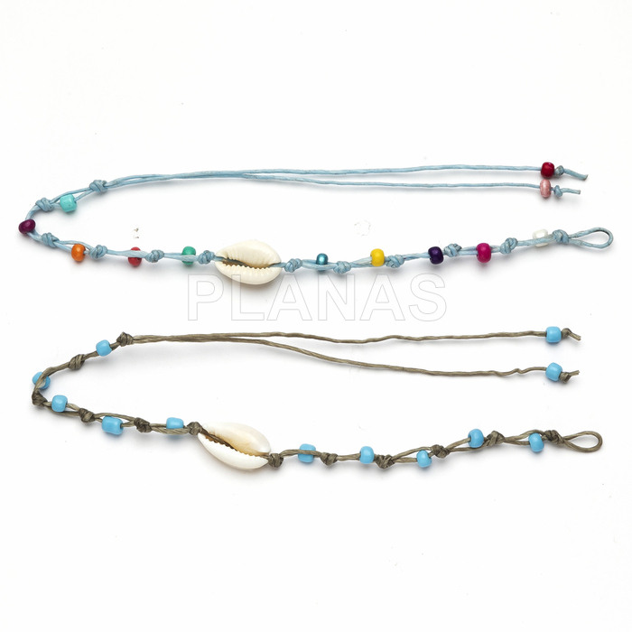 Pulseiras ou tornozeleiras trançadas com conchas.